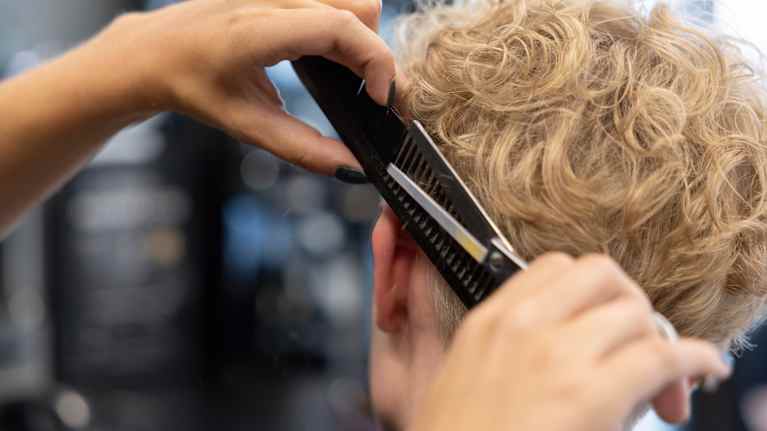  Henkilö on kampaajalla, ja hänen hiuksiaan leikataan.