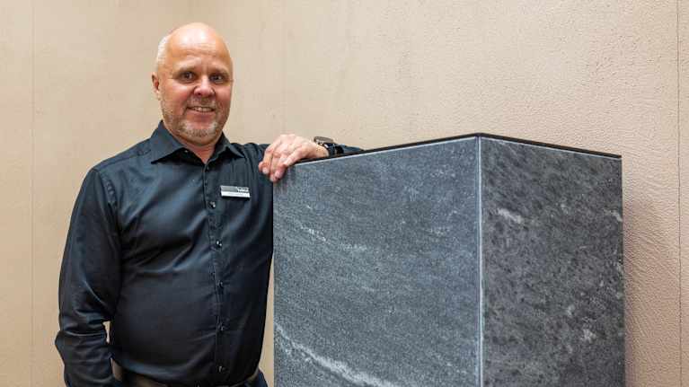 Tulikiven toimitusjohtaja  Heikki Vauhkonen nojaa takkaan Habitare-messuilla ja katsoo kameraan.