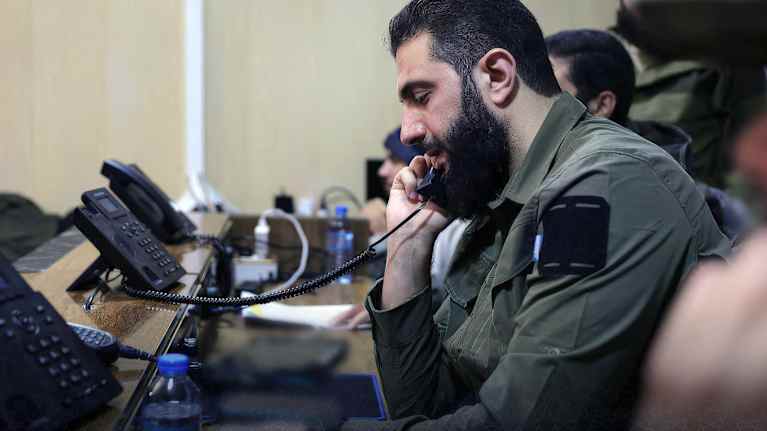 Sotilasasuun pukeutunut Ahmed al-Sharaa puhelimessa.