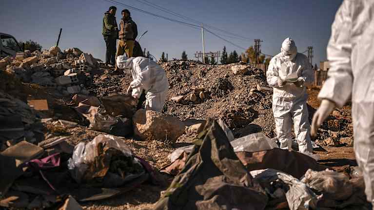 Suojapukuun sonnustautuneita henkilöitä liikkuu joutomaalla.