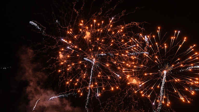 Ilotulitusrakettien värikkäät kipinät valaisevat yötaivaan.