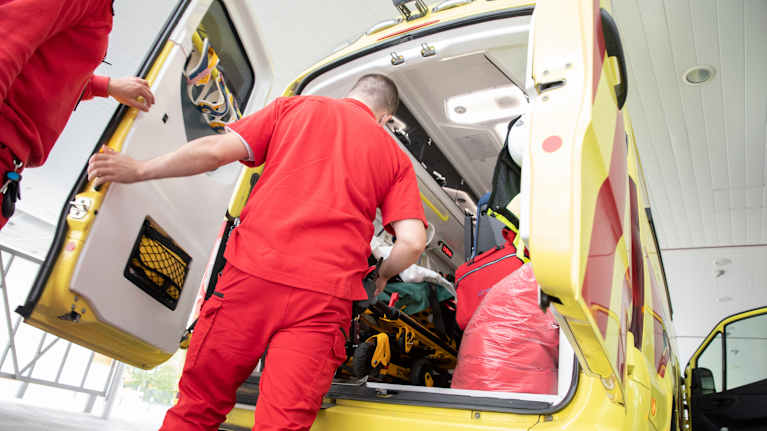 Ensihoitaja on siirtämässä potilasta ambulanssista pois.