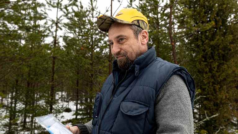 Petoyhdyshenkilö Jan Ylhäinen pitelee kädessään suden ulostetta näytepussissa metsässä.