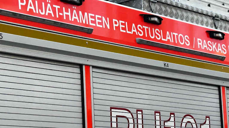 Kuvassa on punaisen paloauton kylki, jossa harmaata ja valkoista tekstiä.