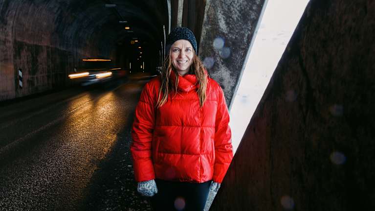 Punaiseen untuvatakkiin pukeutunut henkilö seisoo tunnelissa Ísafjörðurin kylässä Islannissa.