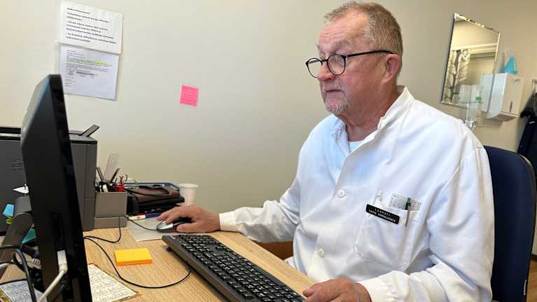 71-vuotias lääkäri Tapio Hämäläinen tutkii potilastietoja tietokoneelta.