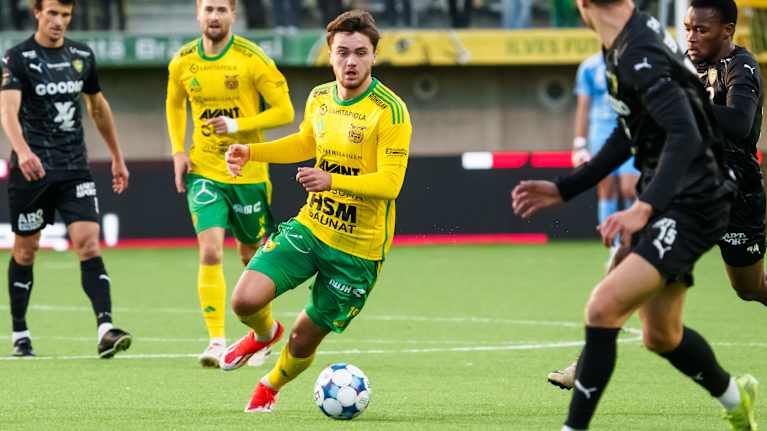 Jalkapallonpelaaja Oiva Jukkola kuljettaa palloa vastustajien välissä.