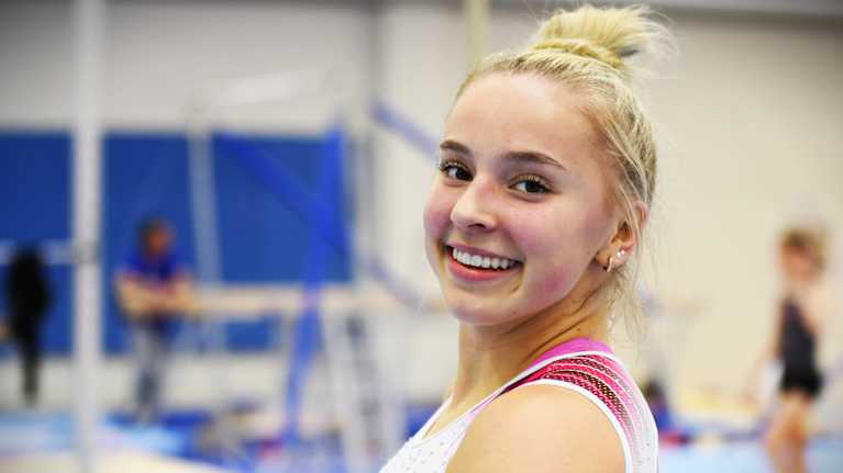 Voimistelija Kaia Tanskanen hymyilee kameralle voimistelusalissa.