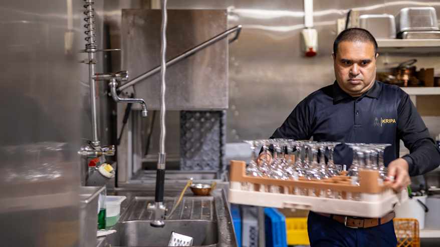 Keittiöapulainen Bhavesh Patel kantaa puhteita laseja ravintolassa.