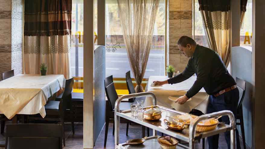 Keittiöapulainen Bhavesh Patel kerää astioita pöydästä.