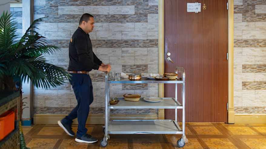 Keittiöapulainen Bhavesh Patel kuljettaa astiakärryä ravintolassa.