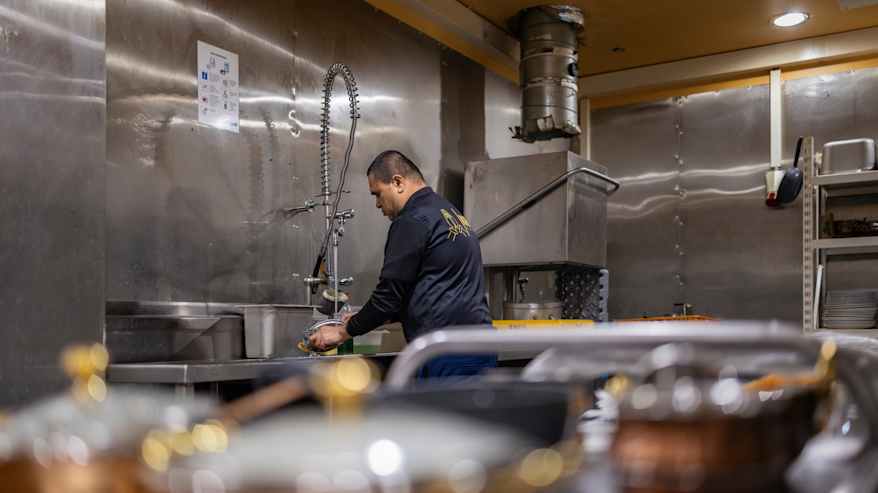 Keittiöapulainen Bhavesh Patel pesee astioita ravintolan keittiössä.