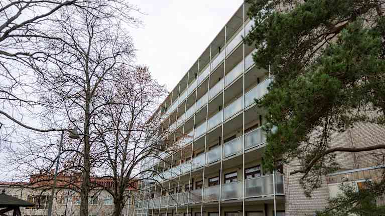 7 kerroksinen valkotiilinen kerrostalo, jonka seinämä on pelkkää parveketta kaltevassa muodossa.