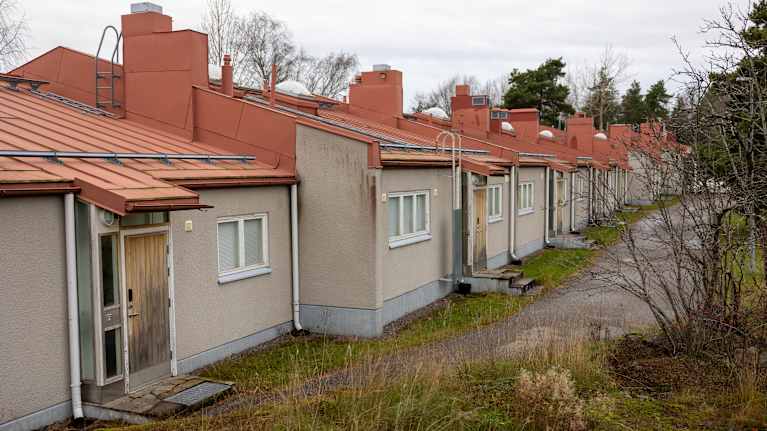 Rivitalo, jossa on harmaaksi rapatut seinät ja punainen peltikatto.