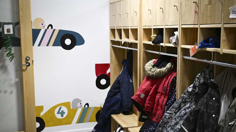 Lastenvaatteita roukkuu päiväkodin naulakossa.