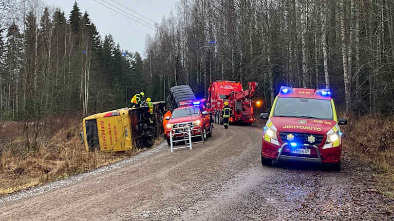 Pelastuslaitoksen ajoneuvoja tiellä ja tien vieressä ojaan kaatunut bussi.