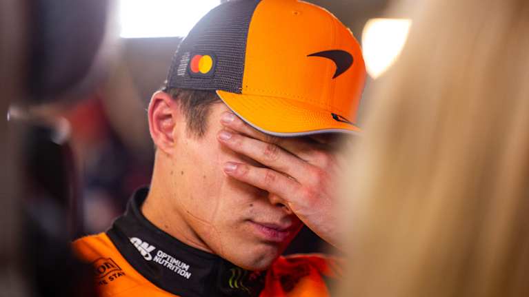Lando Norris peittää kasvonsa kädellään.