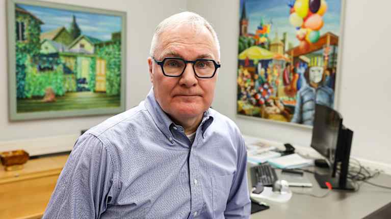 Mies seisoo työhuoneessaan.