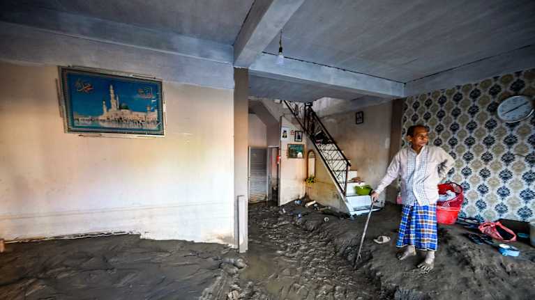 Henkilö seisoo huoneessa mudan keskellä.