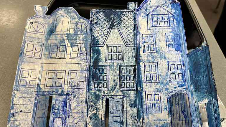 Pahville on piirretty kolme taloa, jotka on leikattu pahvista ääriviivoja myöten. Talot on maalattu sinivalkoisiksi.