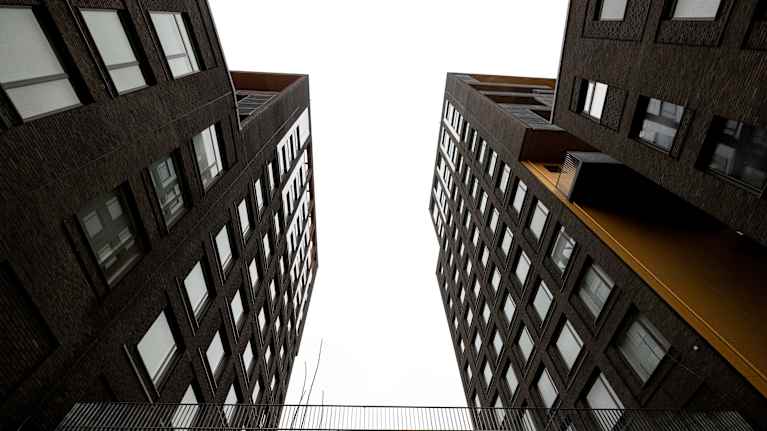 Kaksi tummaa kerrostalorakennusta joiden välissä silta.