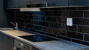 Opiskelija-asunnon yhteistilojen tummapintainen keittiö.