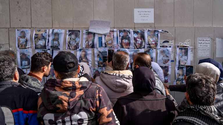 Ihmiset Syyriassa kerääntyvät katsomaan seinään kiinnitettyjä kuvia vainajista.