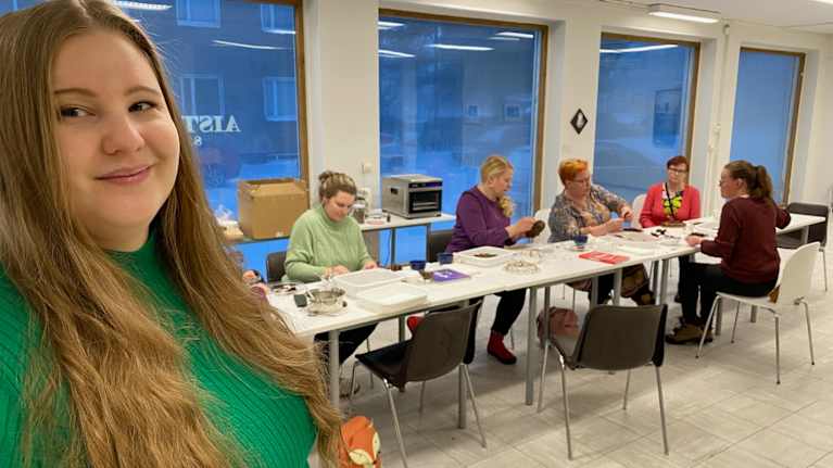 Etualalla kuvassa pitkähiuksinen, vihreäpiatainen nuori nainen, jonka taustalla vaaleamman vihreään paitaan pukeutunut nainen.