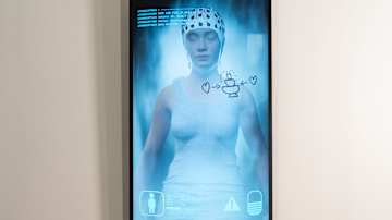 Tekoapinan pää lattialla ja animoitu nainen näytöllä.