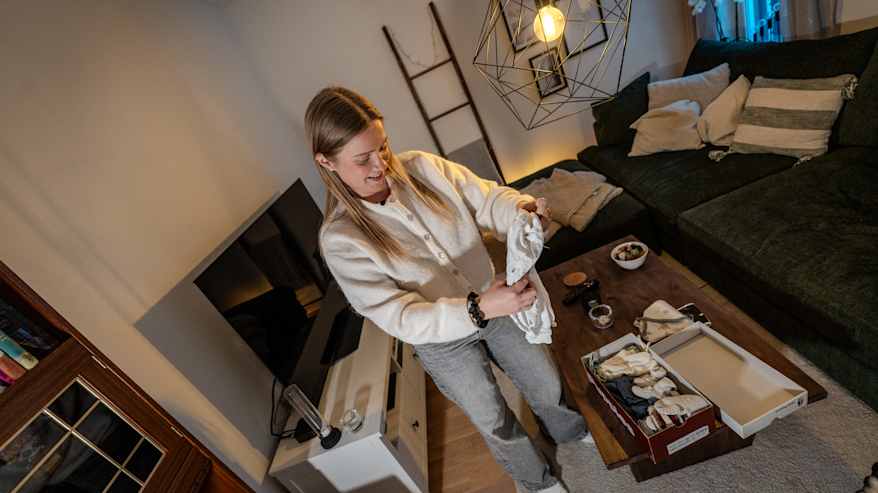 Veera Kauppi pitelee lapsenvaatteita.