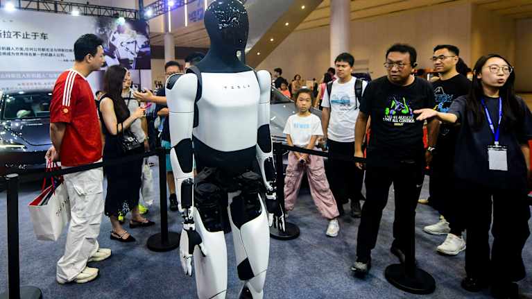 Teslan Optimus -humanoidirobotti katsojien ympäröimänä.