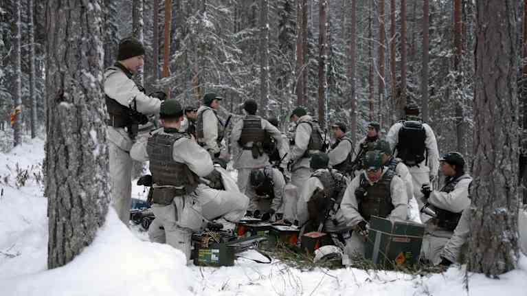 Lumipukuisia sotilaita valmistautumassa maastossa harjoitukseen.
