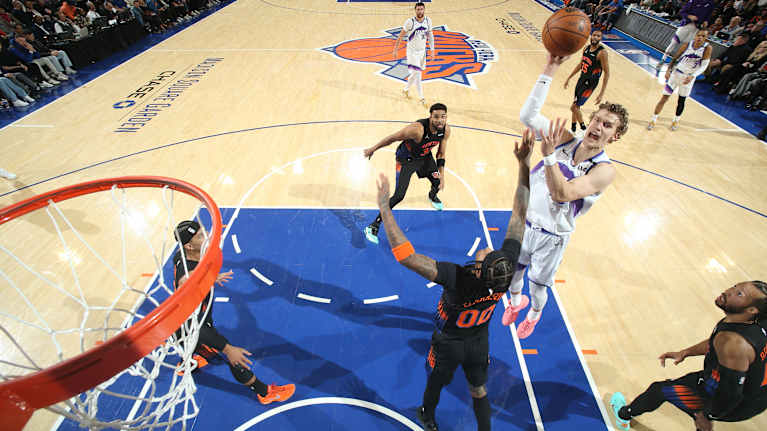 Lauri Markkanen heittää koripalloa vastustajansa yli kohti korirengasta.