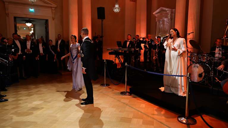 Jenni Vartiainen laulaa orkesterin edessä valkoisessa puvussa.