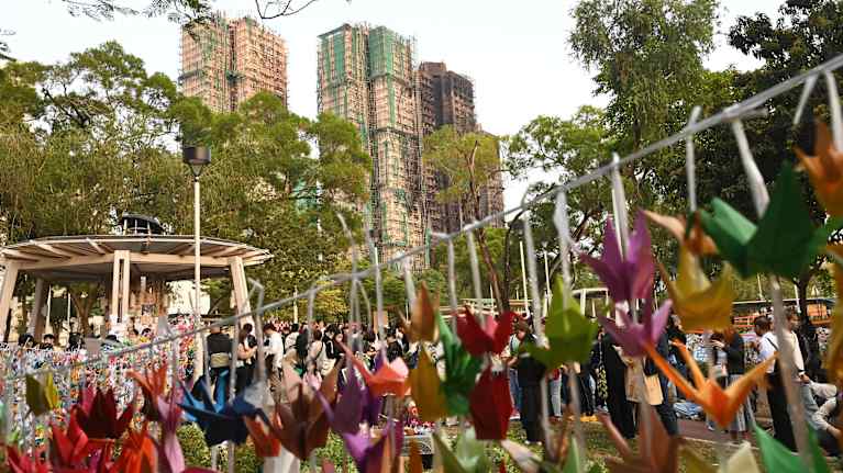 Kukkia ja pehmoleluja roikkuu Hongkongin palopaikan lähellä olevalla muistopaikalla.