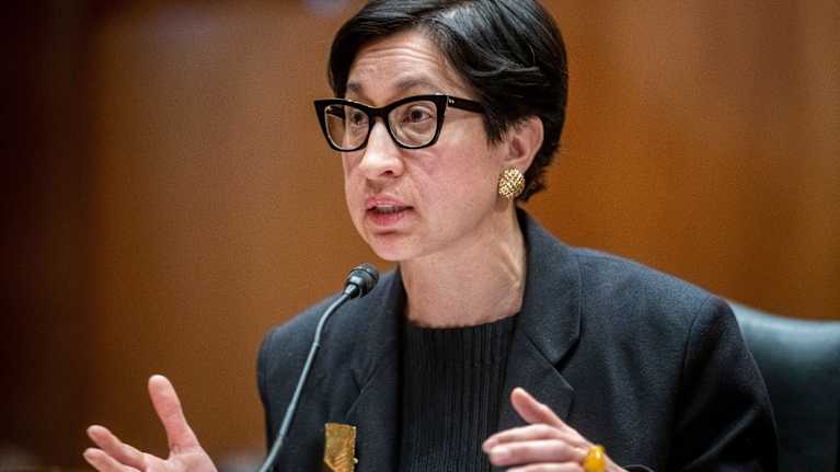 Silmälasipäinen nainen puhuu mikorofoniin.