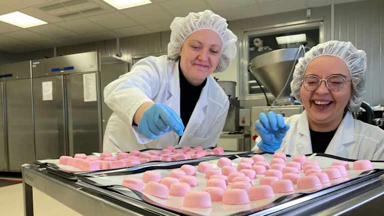 Kaksi naista ottamassa kärrystä vaaleanpunaisia sorbetteja. 