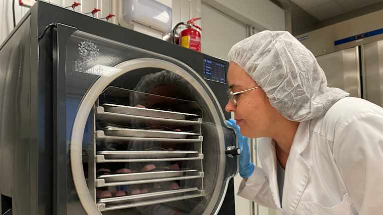 Nainen katsoo kyykistyneenä kuivauslaitteen sisään. 