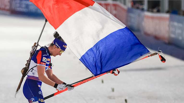 Ampumahiihtäjä maalissa Ranskan lipun kanssa.