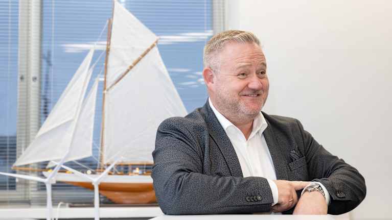 Tom Lind hymyilee iloisesti. Rannekello on esillä.