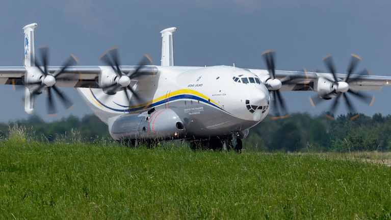 Ukrainalainen Antonov An-22A -kuljetuskone valmistautuu nousuun, sen propellit pyörivät.