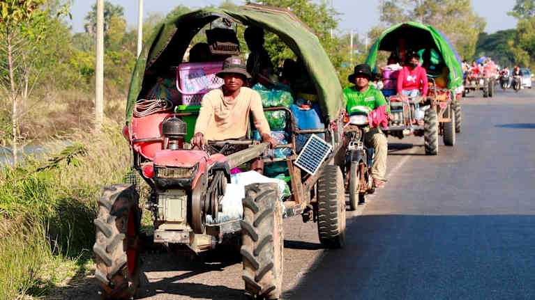 En konvoj med traktorer och motrocyklar kör längs en väg.