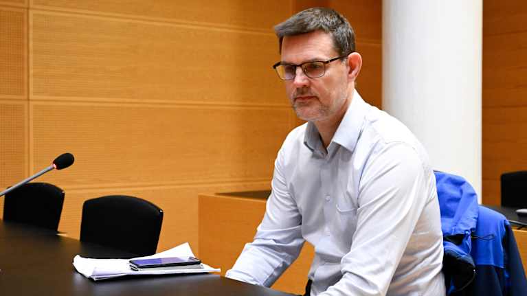 Mies istuu pöydän ääressä.