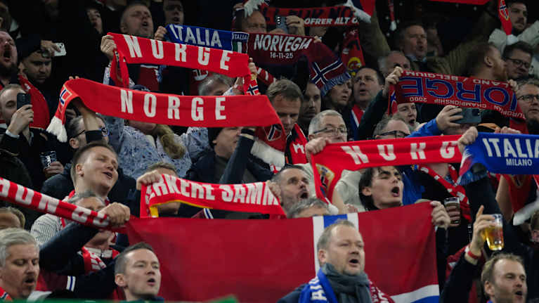 Norjalaiset fanit kannustavat joukkuettaan jalkapallo-ottelussa pitäen ylpeänä esillä punaisia huiveja ja Norjan lippuja.
