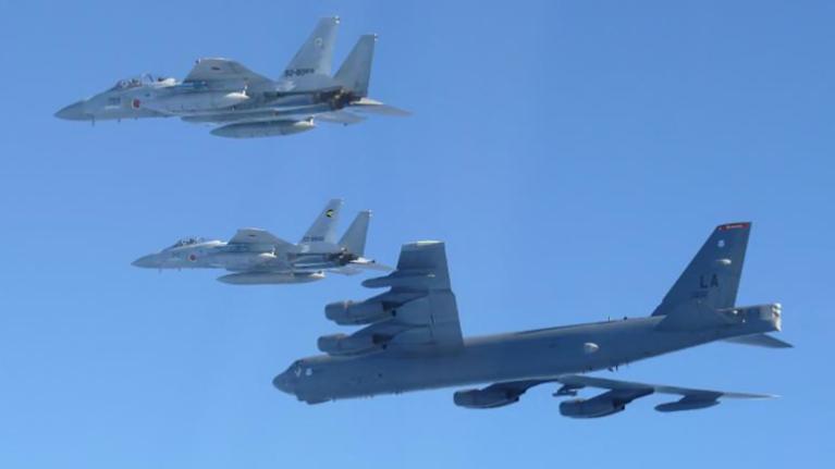 Kaksi hävittäjää ja pommikone lentävät rinnakkain. 