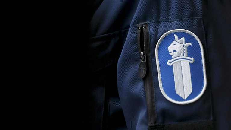 Poliisin hihamerkki olkavarressa.