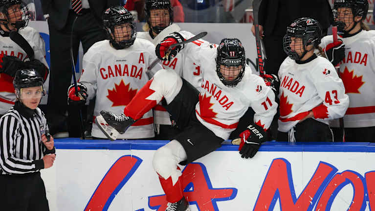 Kanadalaispelaaja Caitlin Kraemer hyppää laidan yli kentälle.