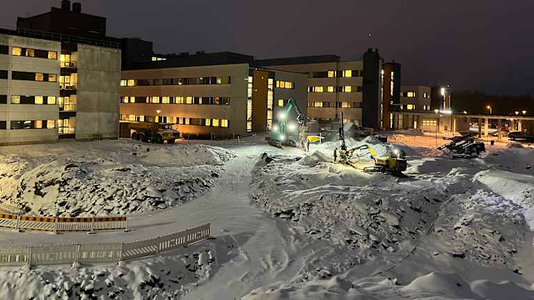 Lunta ja kaivureita pimeällä rakennustyömaalla Seinäjoen keskussairaalassa.