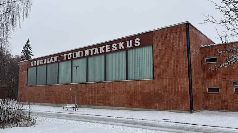 Iso punaisista tiilistä tehty rakennus, jonka seinässä lukee Kourulan toimintakeskus.