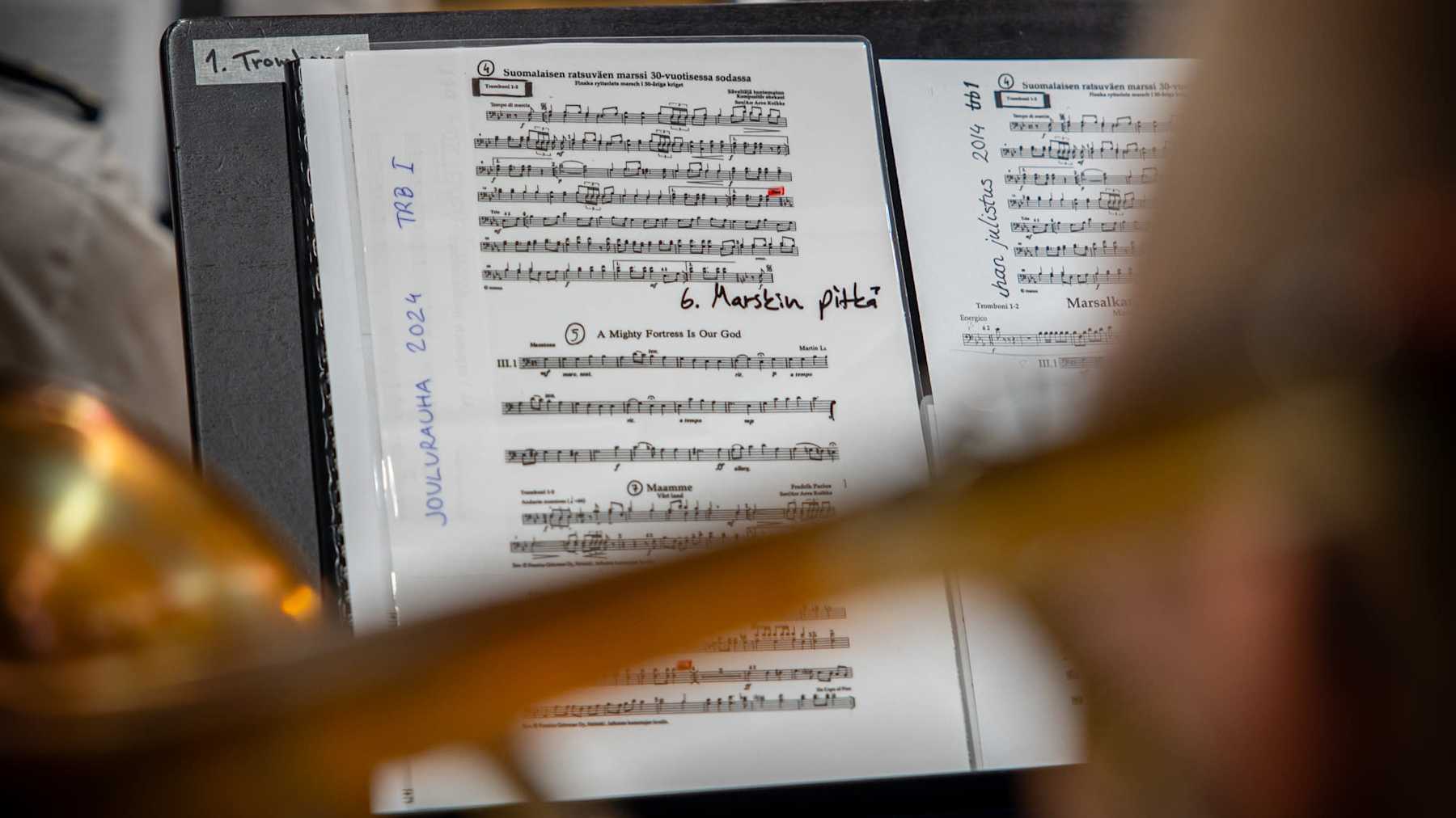 Trumpetin soittaja soittaa nuoteista. Taustalla näkyy muita muusikkoja.
